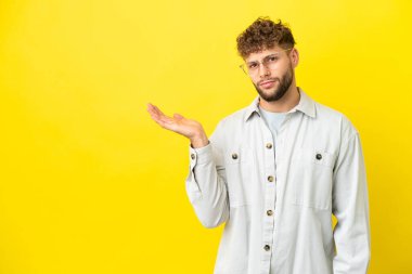 Sarı arka planda izole edilmiş yakışıklı beyaz bir adam. Şüpheleri var.