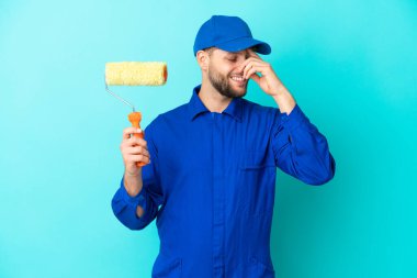 Ressam beyaz adam mavi arka planda izole edilmiş gülüyor.