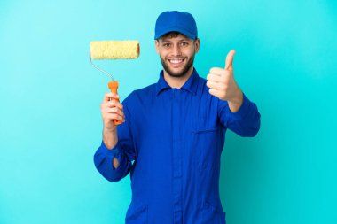 Kafkasyalı ressam mavi arka planda izole edildi. Başparmakları havada çünkü iyi bir şey oldu.
