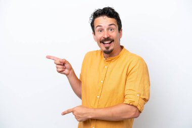 Young man with moustache isolated on white background surprised and pointing side