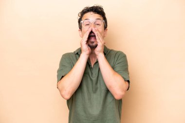 Beyazlı genç adam bej arka planda izole edilmiş bağırıyor ve bir şey duyuruyor.