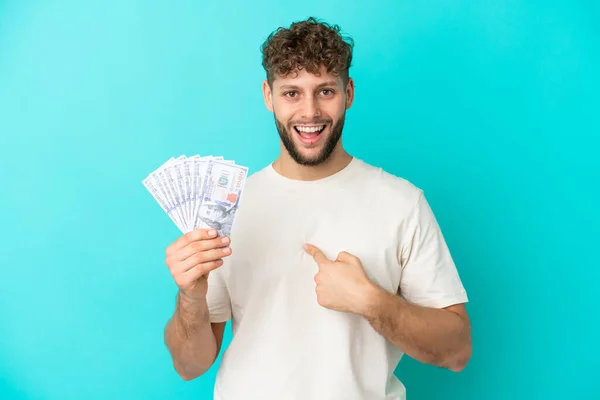 Νεαρός Καυκάσιος Παίρνει Πολλά Χρήματα Απομονωμένος Μπλε Φόντο Έκφραση Έκπληξη — Φωτογραφία Αρχείου