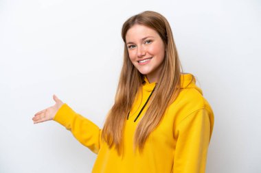 Beyaz arka planda soyutlanmış beyaz tenli genç bir kadın davet edilmek için ellerini yana uzatıyor.