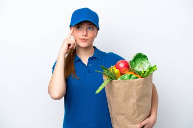 Genç teslimatçı kadın beyaz arka planda izole edilmiş bir paket yiyecek alıyor. Şüpheleri ve düşünceleri var.
