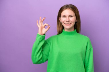 Mor arka planda izole edilmiş genç bir İngiliz kadın parmaklarıyla işaret veriyor.