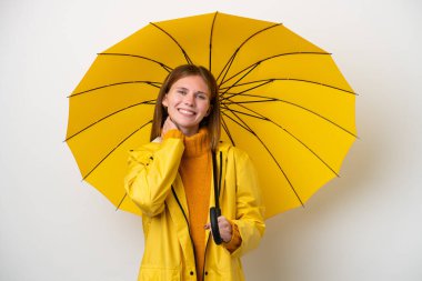 Yağmura dayanıklı ceketi ve şemsiyesi olan genç İngiliz kadın beyaz arka planda izole edilmiş gülüyor.