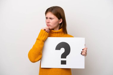 Beyaz arka planda izole edilmiş genç bir İngiliz kadın soru işareti olan bir pankart tutuyor ve düşünüyor.