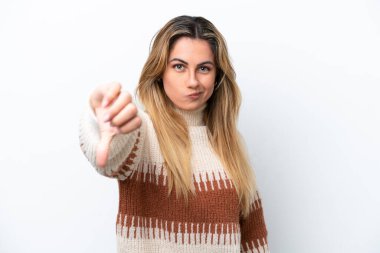 Beyaz arka planda izole edilmiş genç beyaz kadın olumsuz ifade ile baş parmağını aşağı gösteriyor.