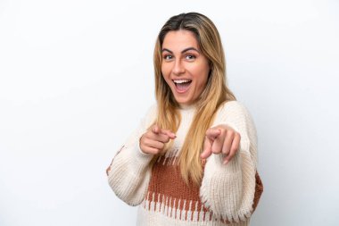 Beyaz arka planda izole edilmiş genç beyaz kadın şaşırmış ve ön tarafı işaret ediyor.