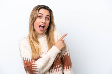 Beyaz arka planda izole edilmiş genç beyaz kadın şaşırmış ve işaret ediyor.