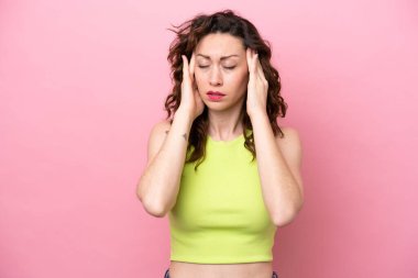 Pembe arka planda izole edilmiş, başı ağrıyan beyaz bir kadın.