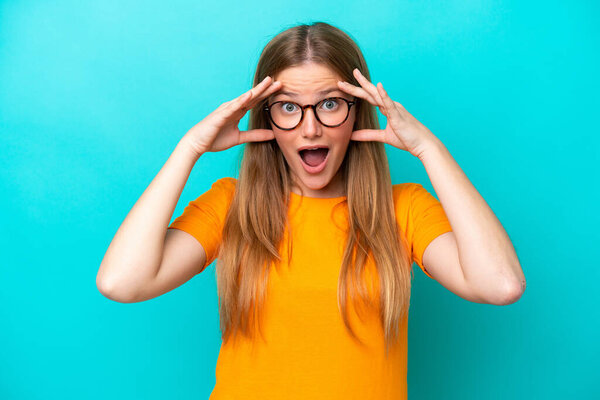 Молодая белая женщина на голубом фоне с удивительным выражением лица