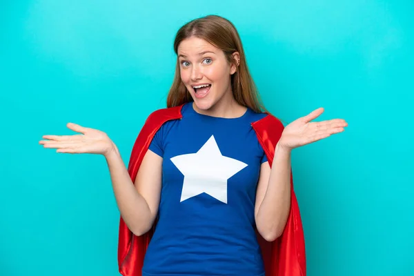 Super Hero caucasian woman isolated on blue background with shocked facial expression