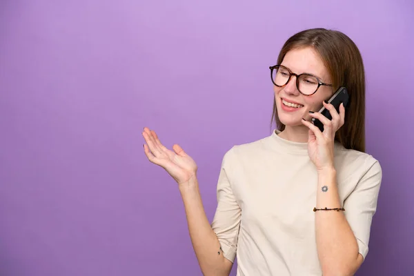 紫色の背景に隔離された若い英語の女性誰かと携帯電話との会話を保つ — ストック写真