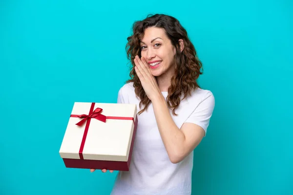 Jonge Blanke Vrouw Met Een Geschenk Geïsoleerd Blauwe Achtergrond Fluisterend — Stockfoto