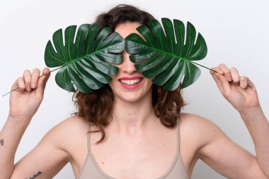 Beyaz arka planda izole edilmiş beyaz bir kadın elinde mutlu bir ifadeyle bir palmiye yaprağı tutuyor. Portreyi kapat