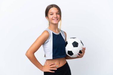 Beyaz arka planda izole edilmiş, kalçasında kollarıyla poz veren ve gülümseyen küçük beyaz kız.