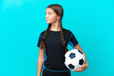 Mavi arka planda, futbol topuyla izole edilmiş küçük beyaz kız.