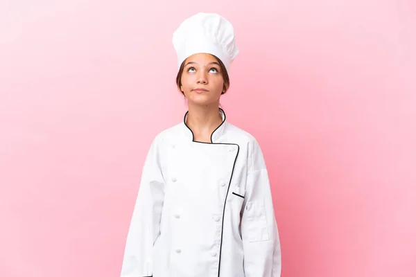 Pouco Caucasiano Chef Menina Isolada Fundo Rosa Olhando Para Cima — Fotografia de Stock