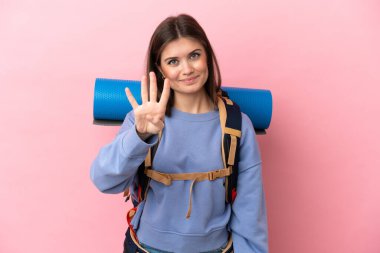 Pembe arka planda izole edilmiş büyük sırt çantalı genç dağcı kadın mutlu ve parmakları olan dört kişi sayıyor.