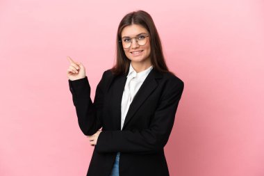 Pembe arka planda izole edilmiş genç beyaz bir kadın parmak işareti yapıyor.