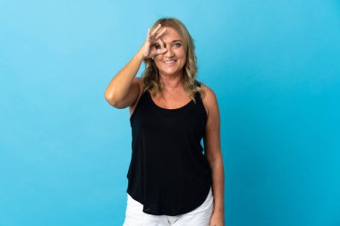 İzole edilmiş arka planda orta yaşlı sarışın kadın parmaklarıyla tamam işareti gösteriyor.