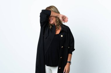 Orta yaşlı sarışın kadın izole edilmiş beyaz arka planda gözlerini elleriyle kapatıyor.