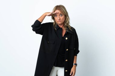 Orta yaşlı sarışın kadın, soyutlanmış beyaz arka planda. Bir şeye bakmak için uzaklara bakıyor.