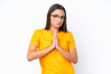 Beyaz arka planda izole edilmiş genç beyaz kadın avuç içlerini bir arada tutuyor. İnsan bir şey ister.