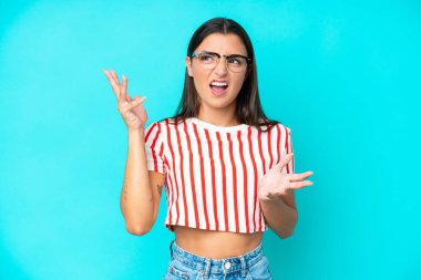 Mavi arka planda izole edilmiş genç beyaz kadın bunalımda.