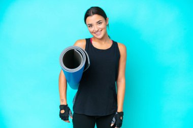 Kafkasyalı genç bir kadın mavi arka planda izole edilmiş, elinde bir paspas ve gülümsüyor.