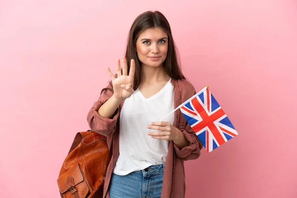 ピンクの背景に孤立した英国の旗を持っている若い白人女性幸せと指で4を数える — ストック写真