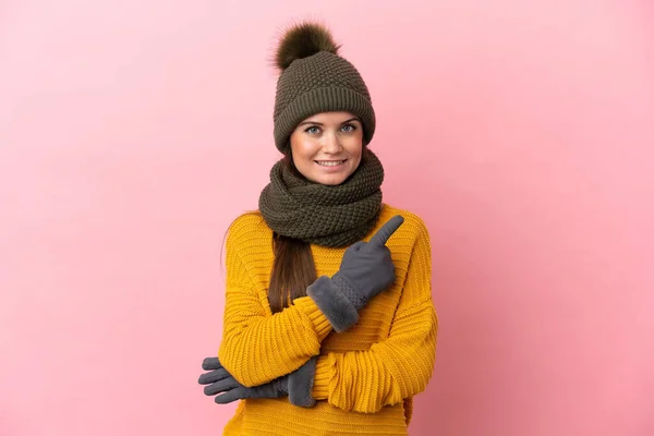 Menina Caucasiana Jovem Com Chapéu Inverno Isolado Fundo Rosa Apontando — Fotografia de Stock