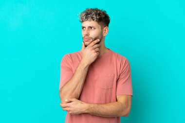 Mavi arka planda izole edilmiş yakışıklı beyaz adam kuşkuları var.