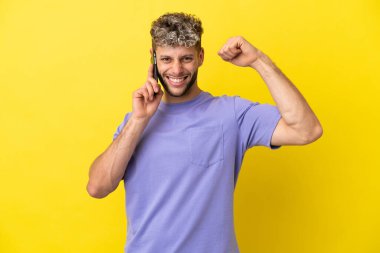 Sarı arka planda izole edilmiş cep telefonu kullanan beyaz bir adam güçlü bir hareket yapıyor.