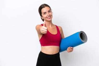 Beyaz arka planda izole edilmiş bir minderi tutarken yoga derslerine giden genç beyaz kadın. Çünkü iyi bir şey oldu.