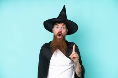 Cadılar bayramında genç bir büyücü mavi arka planda izole edilmiş. Çözümü bulmak için parmağını kaldırıyor.