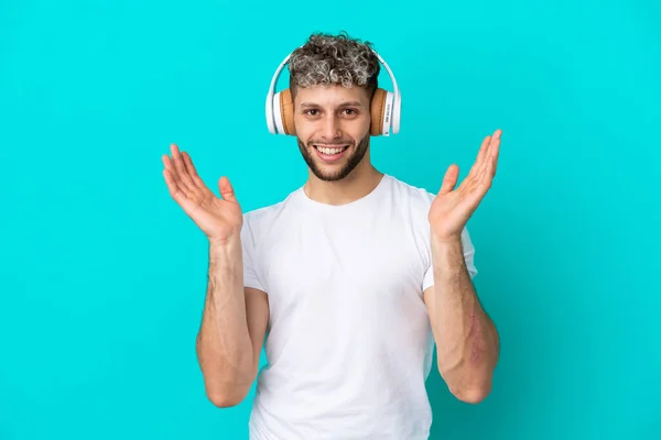Νεαρός Όμορφος Καυκάσιος Άνδρας Απομονωμένος Μπλε Φόντο Έκπληκτος Και Ακούγοντας — Φωτογραφία Αρχείου