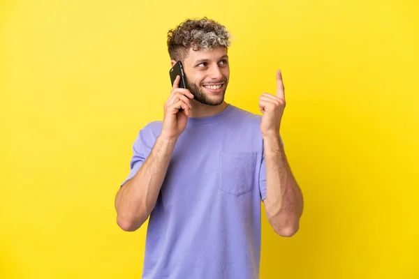 Young Caucasian Man Using Mobile Phone Isolated Yellow Background Pointing — Stock Photo, Image