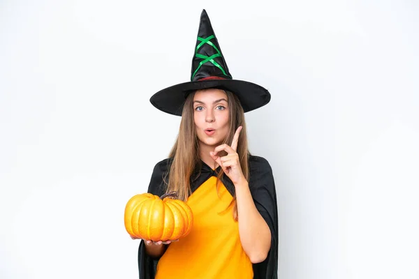 stock image Young caucasian woman costume as witch holding a pumpkin isolated on white background intending to realizes the solution while lifting a finger up