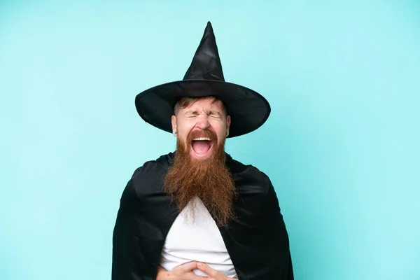 Young wizard in halloween isolated on blue background smiling a lot