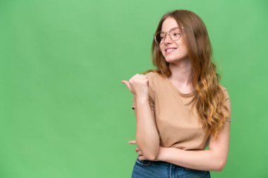 Tecrit edilmiş arka planda genç ve güzel bir kadın bir ürün sunmak için kenarı işaret ediyor.