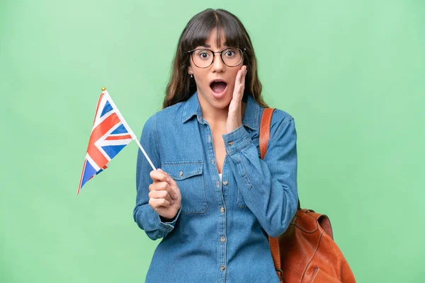 年轻的高加索女人 在孤立的背景下举着英国国旗 脸上带着惊讶和震惊的表情 — 图库照片