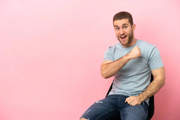 Young Man Sitting Chair Isolated Pink Background Celebrating Victory — Φωτογραφία Αρχείου