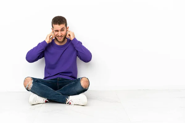 床に座っている若い男欲求不満とカバー耳 — ストック写真