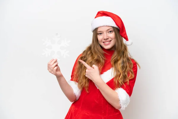 白い背景に隔離された雪の結晶を保持し それを指すクリスマスのドレスを持つ若い白人女性 — ストック写真