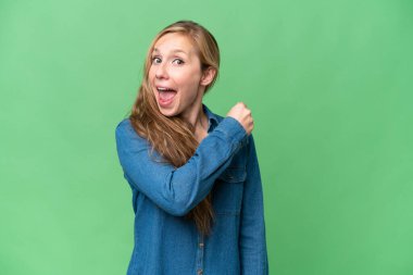 İzole arka plan üzerinde genç sarışın kadın bir zafer kutluyor