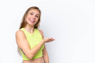 Beyaz arka planda izole edilmiş genç beyaz kadın bir fikir sunuyor ve gülümsüyor.