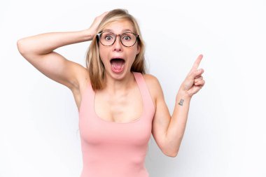 Beyaz arka planda izole edilmiş genç beyaz kadın şaşırmış ve işaret ediyor.