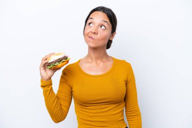 Beyaz arka planda izole edilmiş bir burger tutan genç İspanyol kadın...